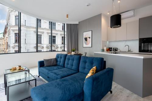 a living room with a blue couch and a kitchen at Apartament Prestige Centrum in Bielsko-Biała