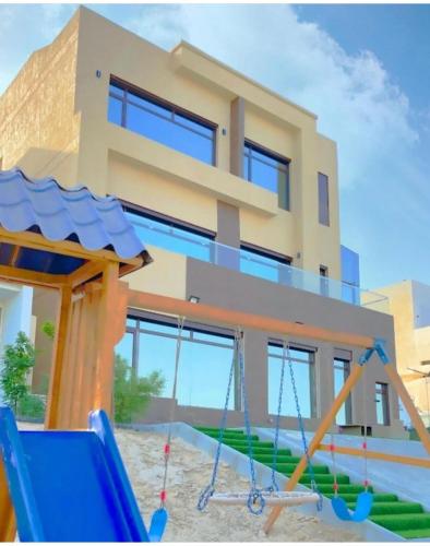 a house with a playground in front of it at منتجع اووه يامال البحري في الخيران OOh Yaa Mal in Al Khīrān