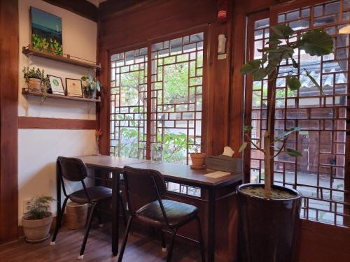een eetkamer met een tafel en stoelen en een boom bij Hanok Got in Seoul
