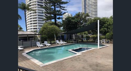 a swimming pool with chairs and a large building at Bayview Bay Apartments and Marina in Gold Coast