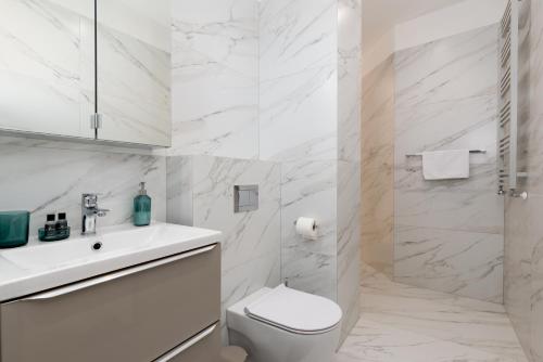 Baño blanco con aseo y lavamanos en Apartament Prestige Centrum, en Bielsko-Biala