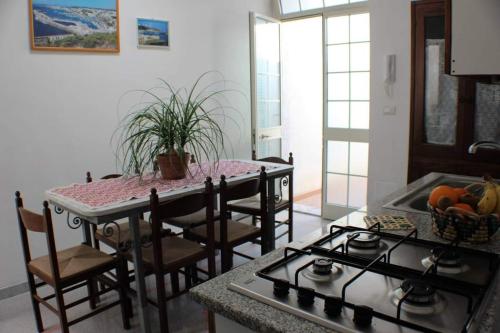 Il comprend une cuisine équipée d'une cuisinière et d'une table avec des chaises. dans l'établissement Casa Fadea, à Gagliano del Capo