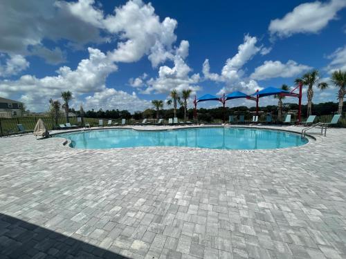 una gran piscina con palmeras y un cielo azul en Cozy suites 4 less en Haines City