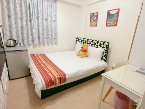 a small bedroom with a teddy bear sitting on a bed at Warm Fengjia LesGo in Taichung
