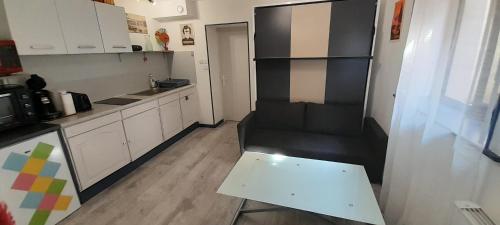 una pequeña cocina con un sofá negro y una mesa en Studio Cosy tout confort Gaillac centre., en Gaillac