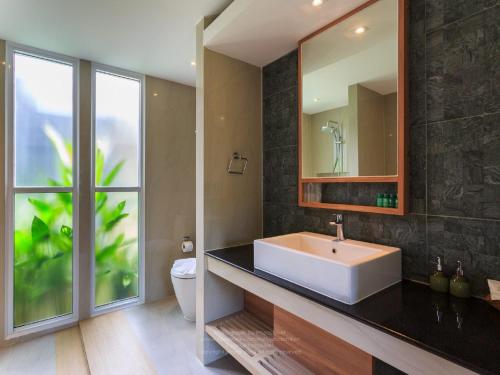 ein Bad mit einem Waschbecken und einem Spiegel in der Unterkunft Khaolak Forest Resort in Khao Lak
