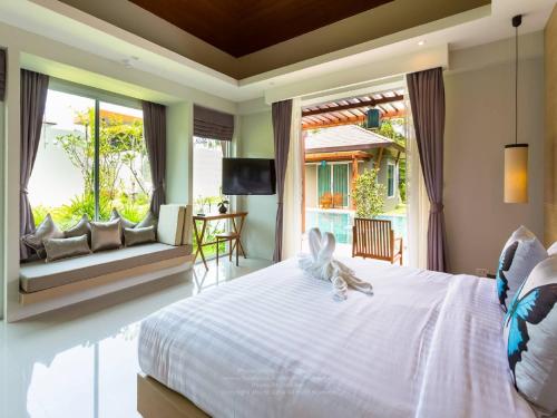 sypialnia z białym łóżkiem i dużym oknem w obiekcie Khaolak Forest Resort w mieście Khao Lak