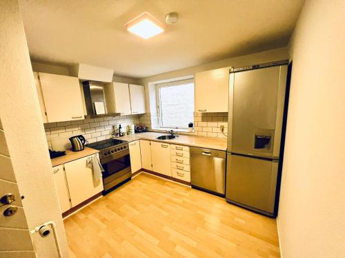 una cocina con armarios blancos y electrodomésticos de acero inoxidable en Apartment in the heart of Aalborg, en Aalborg