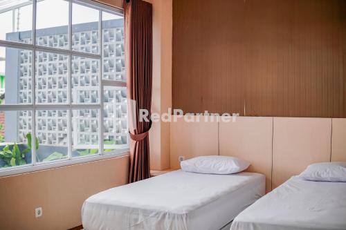 two beds in a room with a window at DManggo Guest House Syariah RedPartner in Tasikmalaya