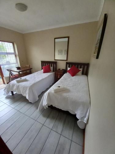 um quarto com 2 camas com lençóis brancos e almofadas vermelhas em Willow Cottage George em George