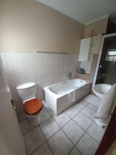 een badkamer met een bad, een toilet en een wastafel bij Willow Cottage George in George