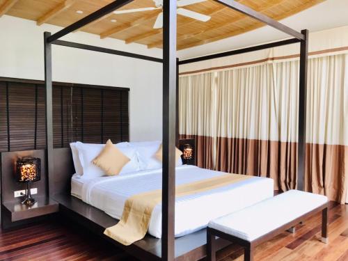 a bedroom with a canopy bed with a bench at Amatapura Beachfront Villa 14, SHA Certified in Ao Nam Mao