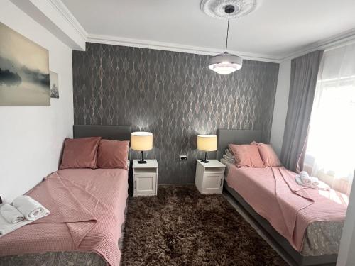 two beds in a bedroom with pink sheets at Blue Sky House in Baloteşti
