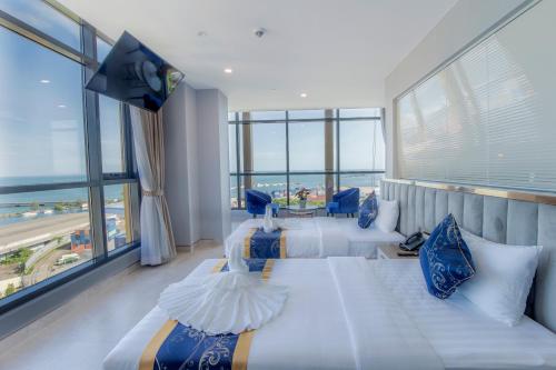 Habitación de hotel con 3 camas y ventana grande. en Seascape Palace Hotel en Sihanoukville