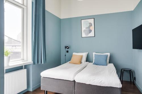 łóżko w pokoju z niebieskimi ścianami w obiekcie Forenom Aparthotel Malmö Varvsstaden w Malmö
