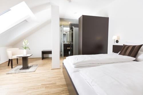 a white bedroom with a bed and a table at Gästezimmer by Jöchlinger in Gerasdorf bei Wien