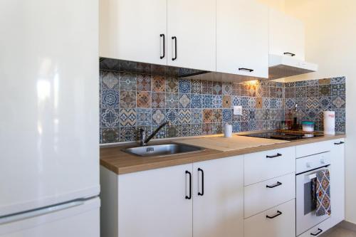 uma cozinha com armários brancos e um lavatório em Villetta a mare Licata em Licata
