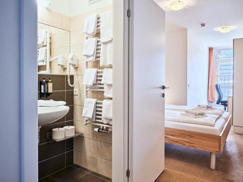 a small bathroom with a bed and a sink at Grafenberg Resort by Alpeffect Hotels in Wagrain