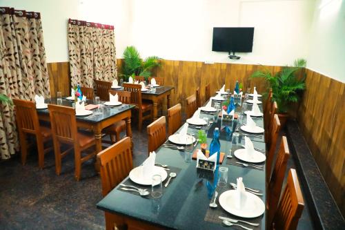 comedor con mesas y sillas y TV en SS Silver Oaks Resort en Yercaud