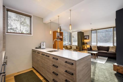 a kitchen with a counter and a living room at Silver Run Thredbo in Thredbo