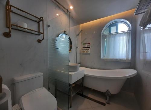 a bathroom with a tub and a sink and a toilet at SongJeong Lesign Hotel in Busan