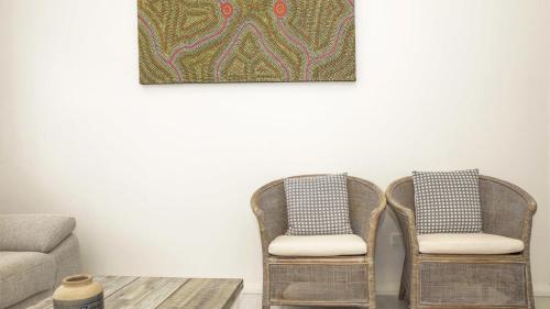 2 Stühle und ein Tisch in einem Wohnzimmer mit einem Bild an der Wand in der Unterkunft Coastline Retreat - Booker Bay in Booker Bay