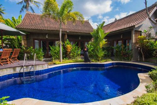 a swimming pool in front of a house at Elemento Homestay Badung in Bringkit
