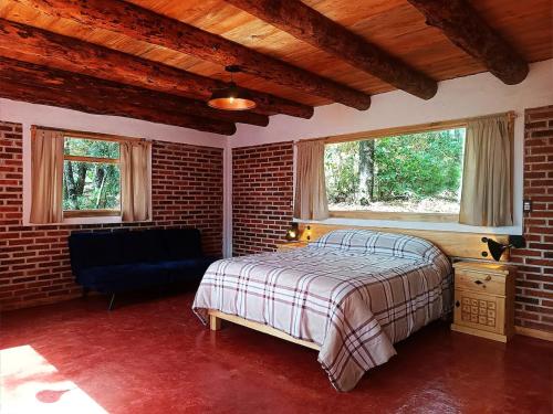 ein Schlafzimmer mit einem Bett und einer Ziegelwand in der Unterkunft Cabaña para pareja en el bosque IB in Acaxochitlán