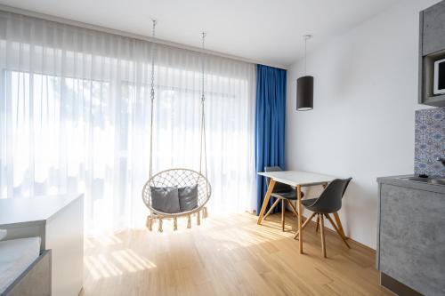 ein Wohnzimmer mit einem Tisch, Stühlen und einem Fenster in der Unterkunft Arbio I Urbanstay Serviced Studios & Apartments in Graz