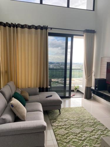 uma sala de estar com um sofá e uma grande janela em Eco Nest 3 Bedroom Duplex Apartment em Nusajaya