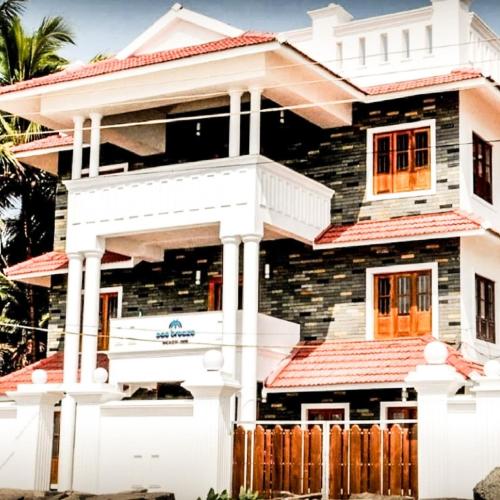 a house with a white fence in front of it at Sea Breeze Beach Inn in Kannur