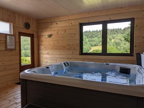 a large tub in a wooden room with a window at La source in Sondernach