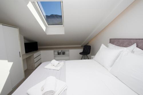 a bedroom with a white bed and a window at Luxury Penthouse Adriatic Blue - On the beach in Tučepi