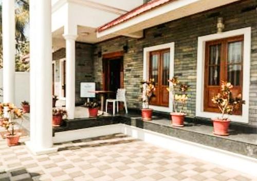 a house with potted plants in front of it at Sea Breeze Beach Inn in Kannur