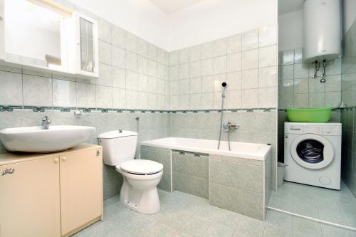 a bathroom with a toilet sink and a washing machine at Secluded family friendly house Kapelica, Labin - 5536 in Raša