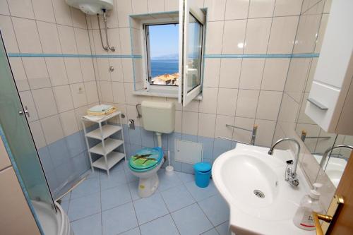łazienka z umywalką, toaletą i oknem w obiekcie Apartments and rooms with WiFi Senj - 5560 w mieście Senj