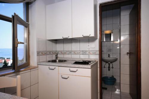 een keuken met witte kasten, een wastafel en een raam bij Apartments with WiFi Crikvenica - 5555 in Crikvenica