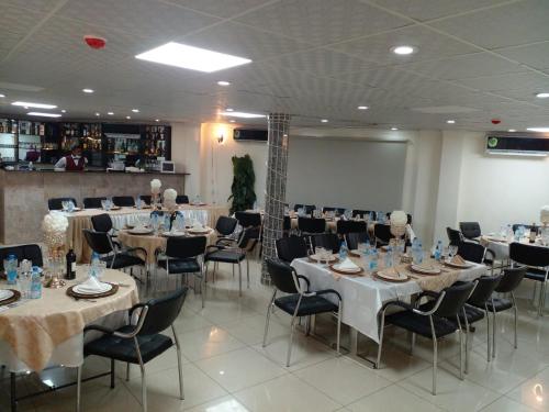 un salón de banquetes con mesas, sillas y una pantalla en Hôtel Freesia, en Yaoundé