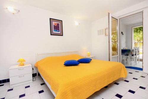 a bedroom with a yellow bed with two blue pillows at Apartments with a parking space Bol, Brac - 5642 in Bol