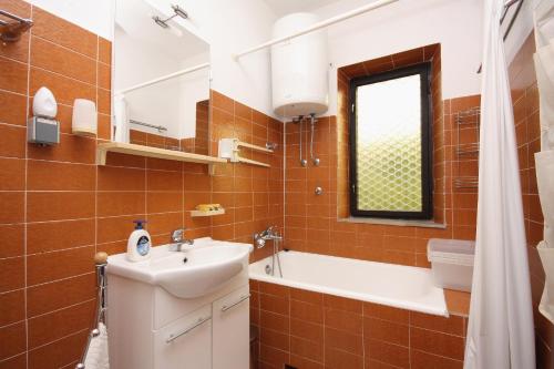 a bathroom with a sink and a bath tub at Apartments by the sea Sumartin, Brac - 5619 in Sumartin