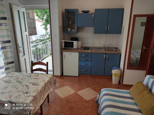 a kitchen with blue cabinets and a table and a sink at Apartments by the sea Selce, Crikvenica - 5550 in Selce