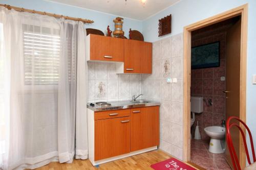 uma pequena cozinha com armários de madeira e um lavatório em Apartments for families with children Crikvenica - 5554 em Crikvenica