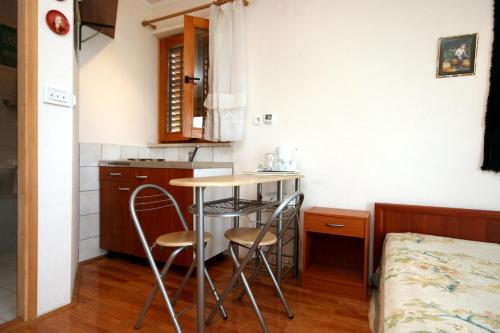 uma pequena cozinha com duas cadeiras e uma mesa num quarto em Apartments for families with children Crikvenica - 5554 em Crikvenica