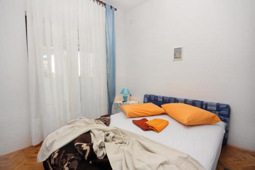 a bed with two orange pillows in a room at Apartments by the sea Mirca, Brac - 5655 in Mirce