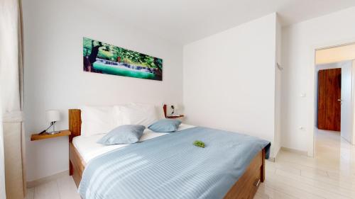 um quarto branco com uma cama com almofadas azuis em Zen-Pok House on the Beach - Pokrivenik em Zastražišće