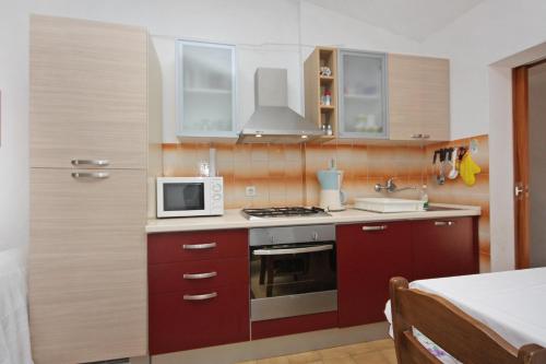 a small kitchen with a microwave and a stove at Apartments with parking space Supetar, Brac - 5653 in Supetar