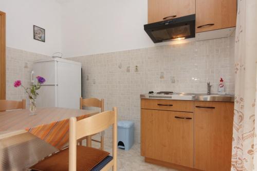 a kitchen with a table and a white refrigerator at Apartments by the sea Sumartin, Brac - 5620 in Sumartin