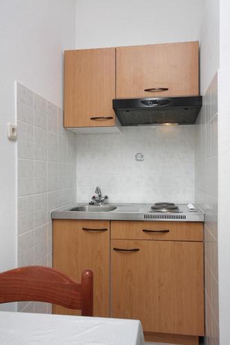 a kitchen with wooden cabinets and a sink at Apartments by the sea Sumartin, Brac - 5620 in Sumartin