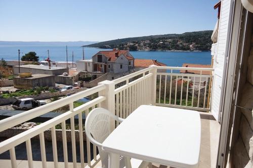 a white chair on a balcony with a view of the ocean at Apartments by the sea Sumartin, Brac - 5620 in Sumartin