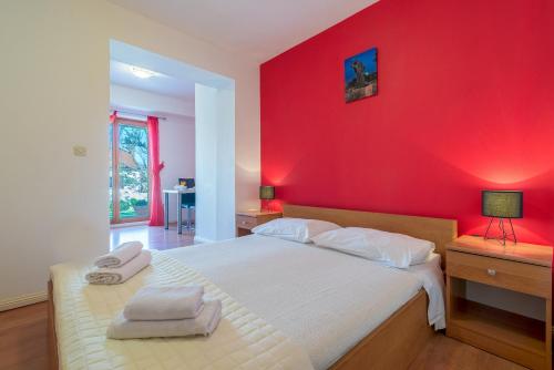 - une chambre avec un mur rouge et un lit blanc dans l'établissement Apartments by the sea Nin, Zadar - 5666, à Nin